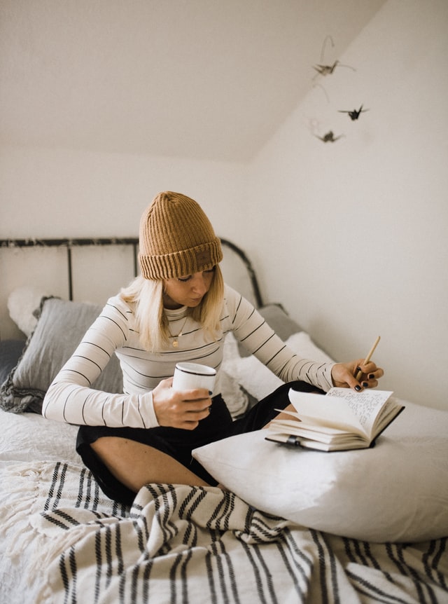 girl writing in her journal with coffee in comfy clothes